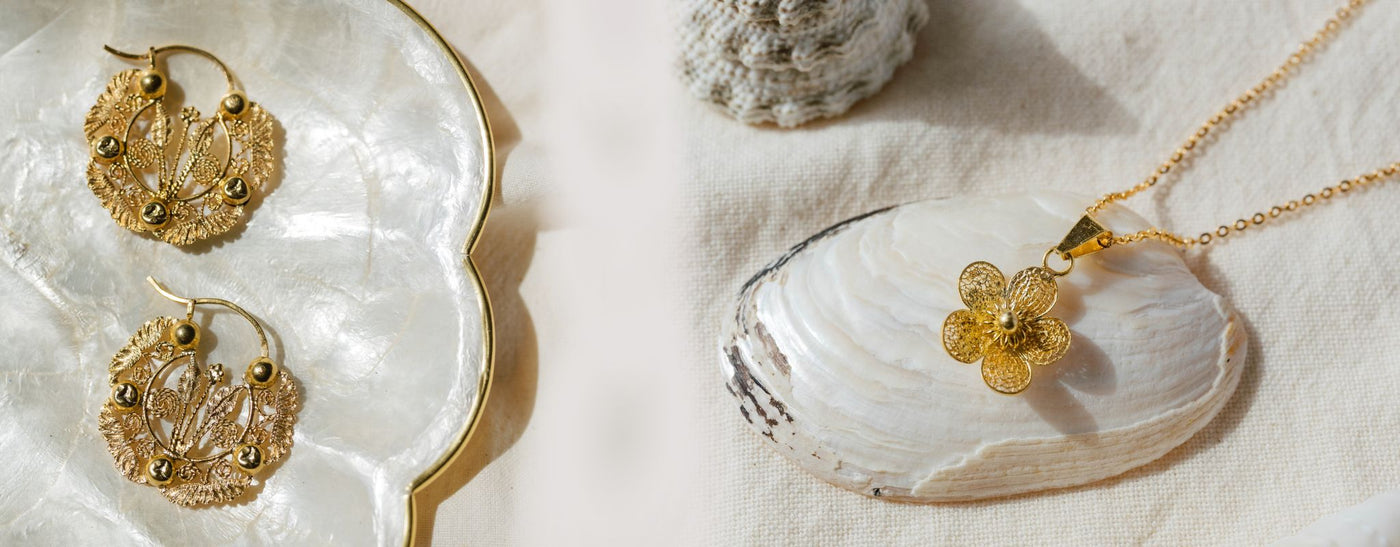 Filipino gold filigree jewelry - a pair of creolla earrings on the left and sampaguita necklace on the right with shells scattered around.